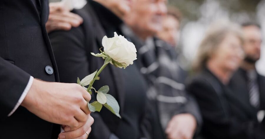 Person holding a white rose at a funeral, illustrating the common causes of wrongful death.